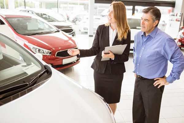 Smiling businesswoman showing car to customer