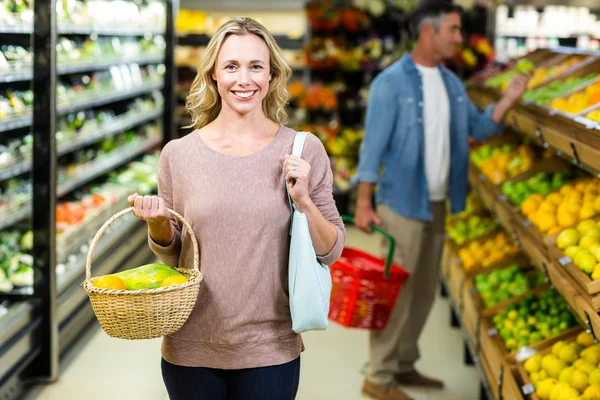 Pretty blonde woman holding vegetables basket