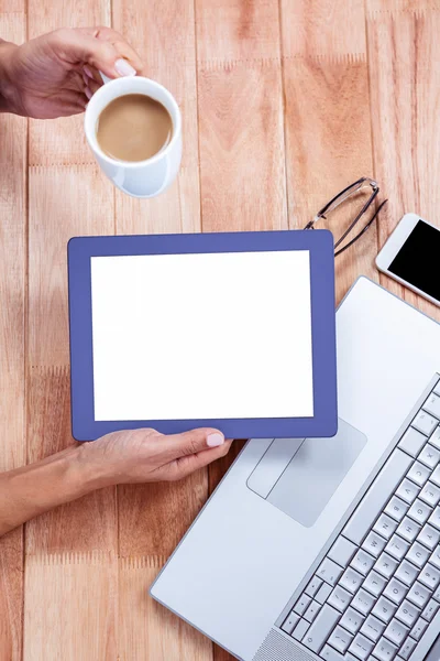 Overhead of feminine hands holding tablet and coffee