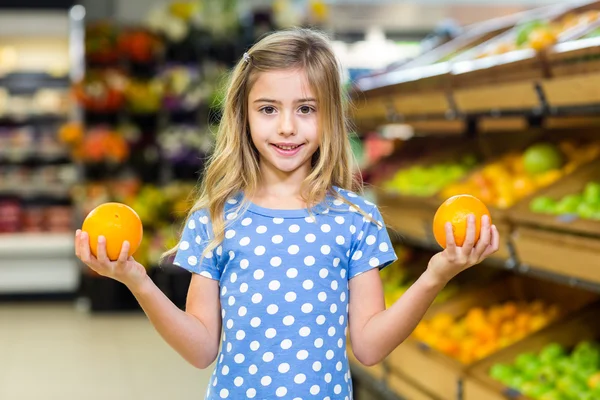 Smiling young girl holding oranges