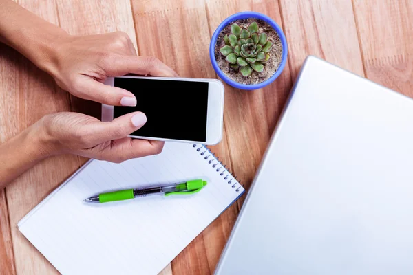 Feminine hands holding smartphone and taking notes