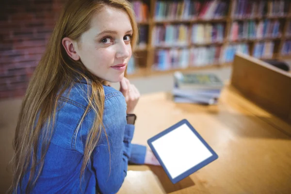 Student using tablet in library looking back at the camera