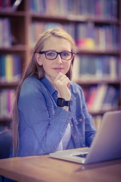 Student with smartwatch using laptop in library