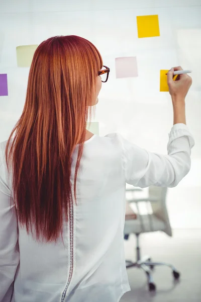 Attractive hipster woman writing on sticky notes