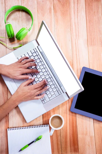 Overhead of feminine hands typing on laptop