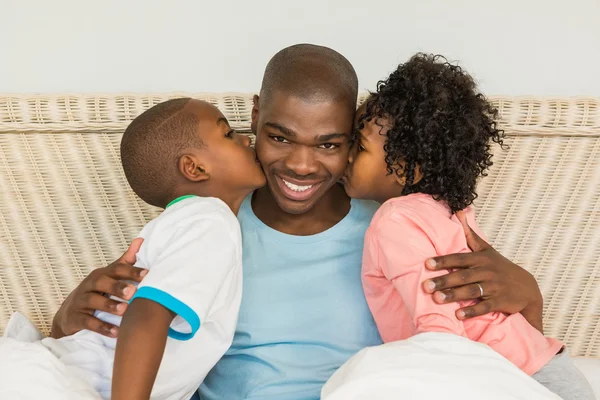 Children kissing father in bed