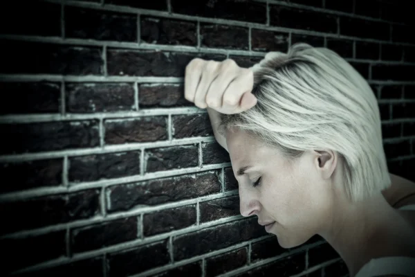 Sad blonde woman crying with head on hands