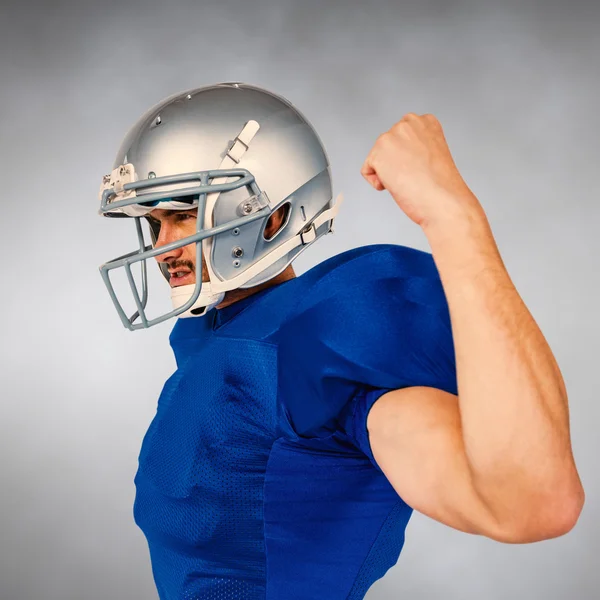 American football player looking away while flexing muscles