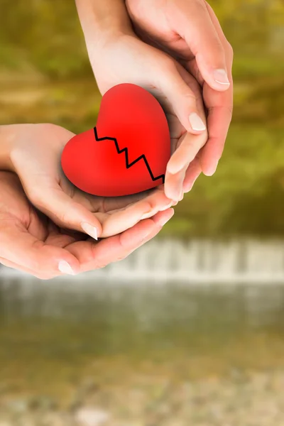 Couple holding broken heart in hands