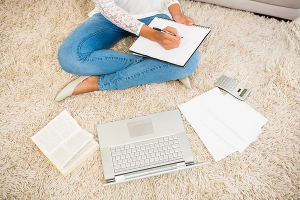 Woman writing note while using her laptop