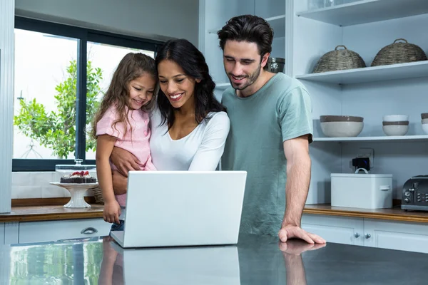 Smiling parents using laptop with daughter