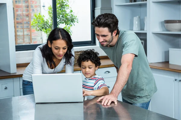 Smiling parents using laptop with son