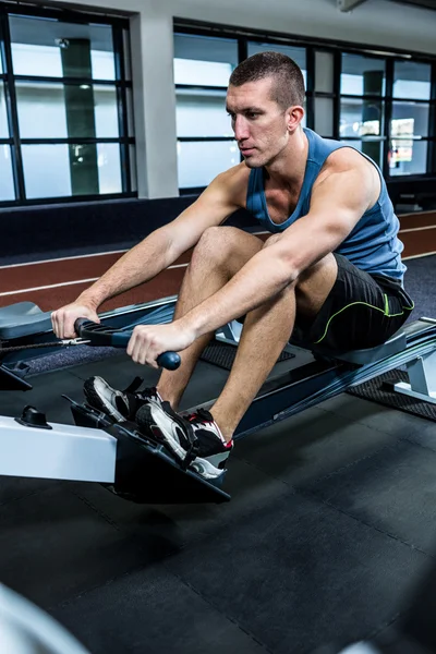 Muscular man using rowing machine