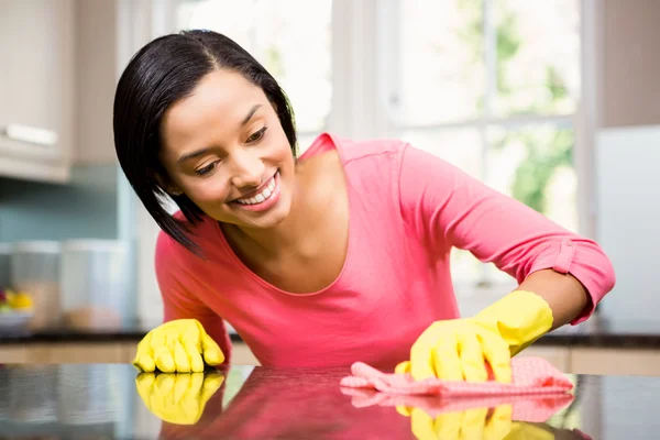Smiling brunette cleaning kitchen counter