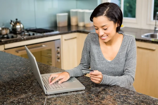 Brunette using laptop and holding credit card