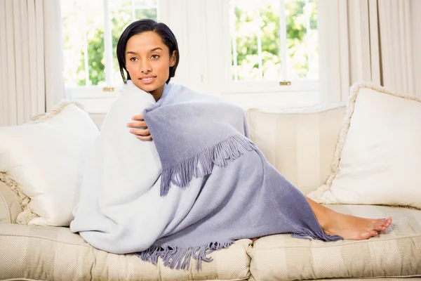 Attractive brunette on sofa under blanket