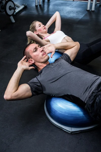 Fit couple doing sit ups on bosu ball