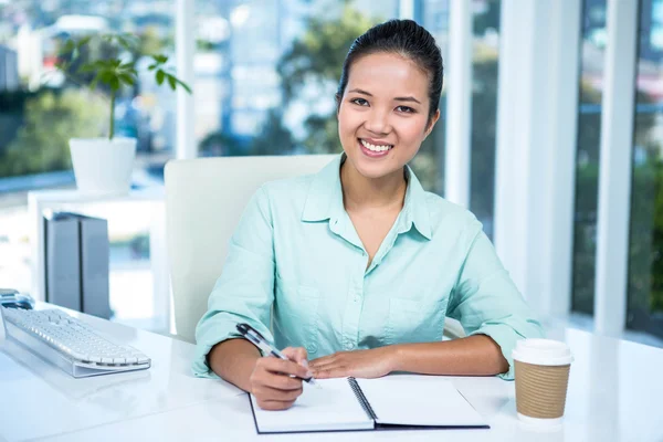 Smiling businesswoman writing notes