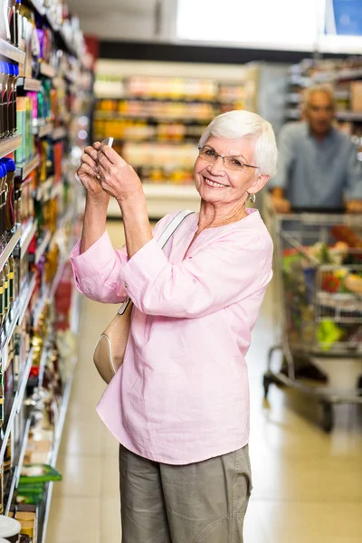 Senior woman taking a picture of product on shelf