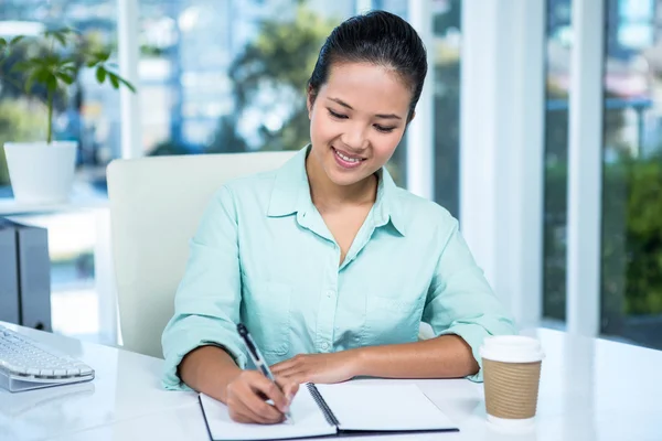 Smiling businesswoman writing notes