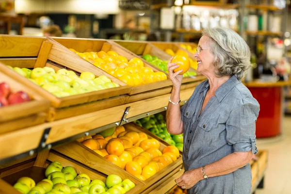 Smiling senior woman smelling orange