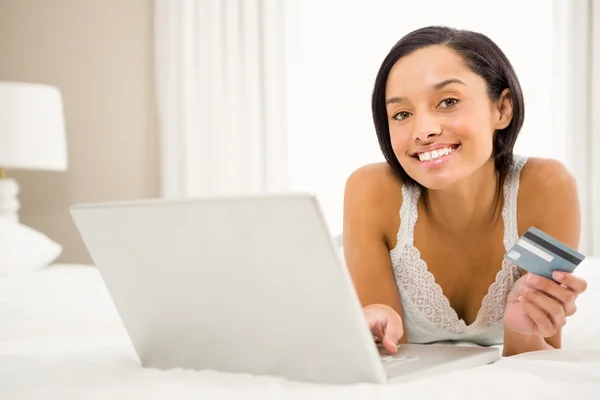 Brunette using laptop and holding credit card