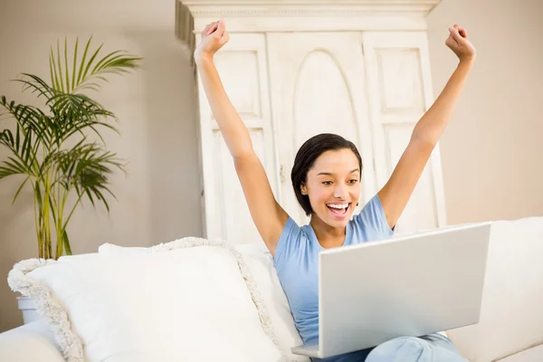 Woman using laptop and raising arms