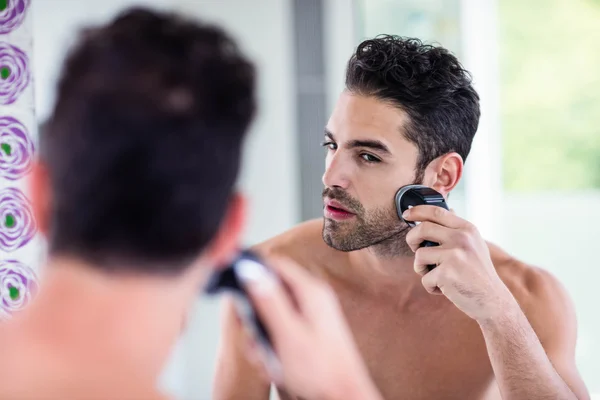 Handsome man shaving in mirror