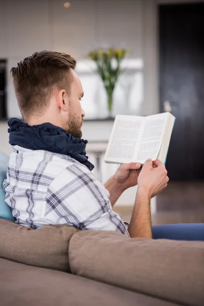 Man reading book on couch