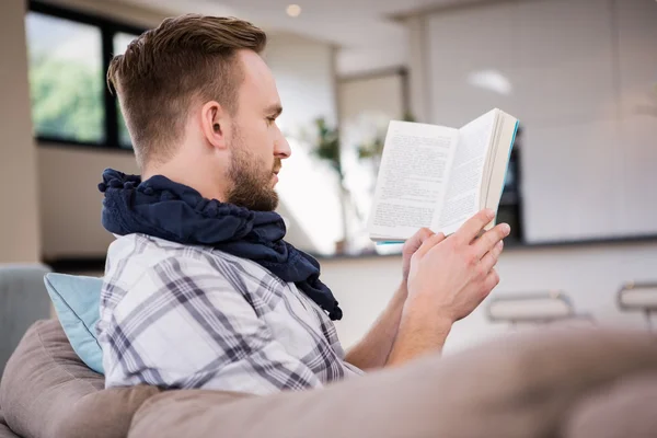 Handsome man reading book on couch