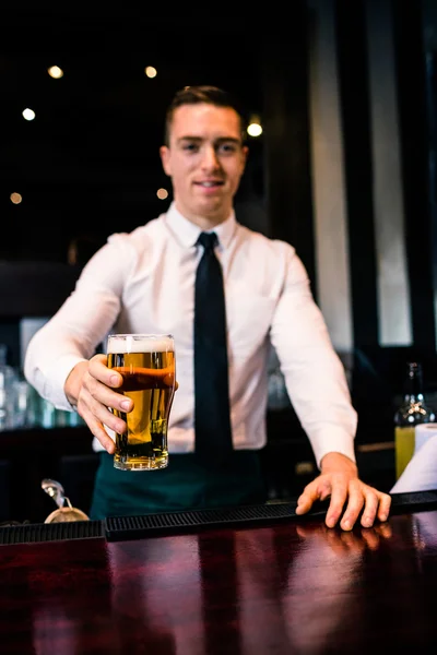 Barman serving pint of beer