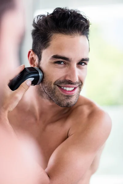 Handsome man shaving in mirror