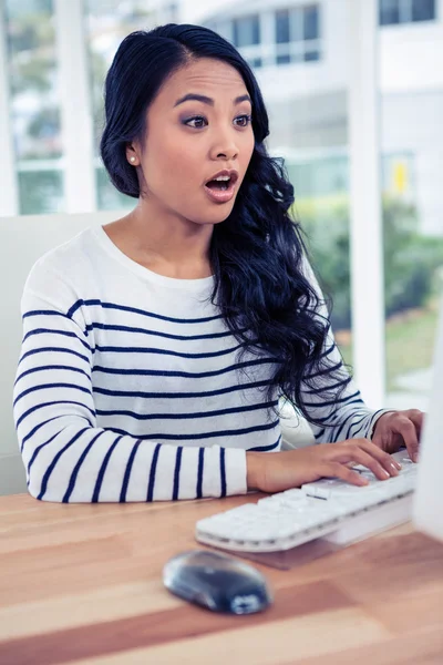 Surprised Asian woman using computer