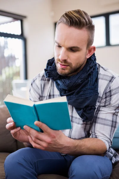 Handsome man reading book on couch