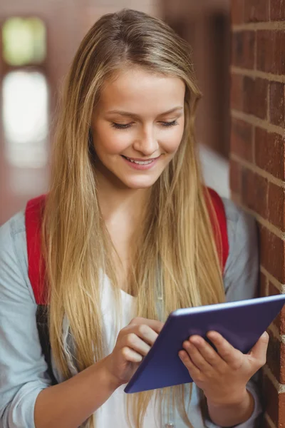 Smiling student using tablet in the hallway