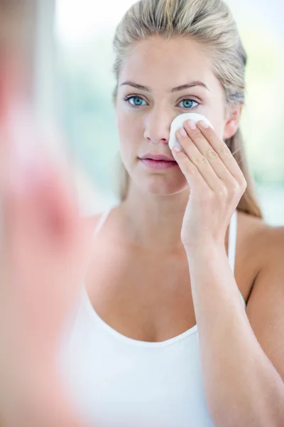 Woman wiping face with cotton pad