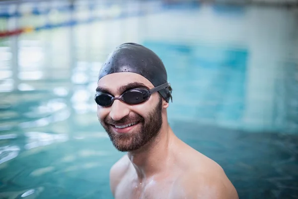 Smiling man wearing swim cap and goggles