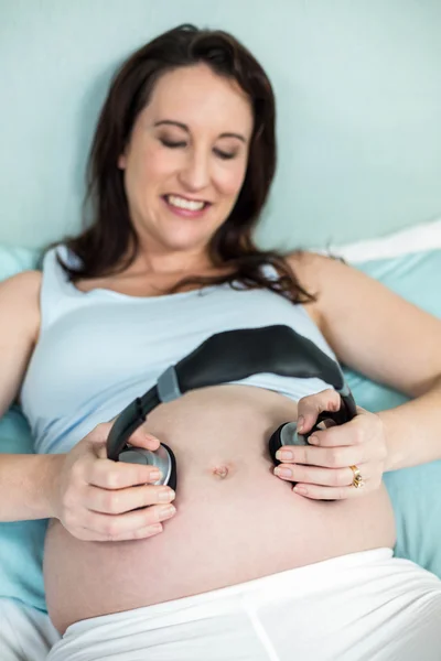 Pregnant woman putting headphones