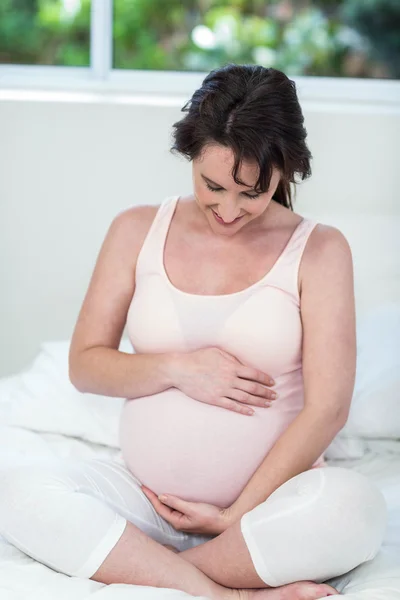 Smiling pregnant woman touching her belly