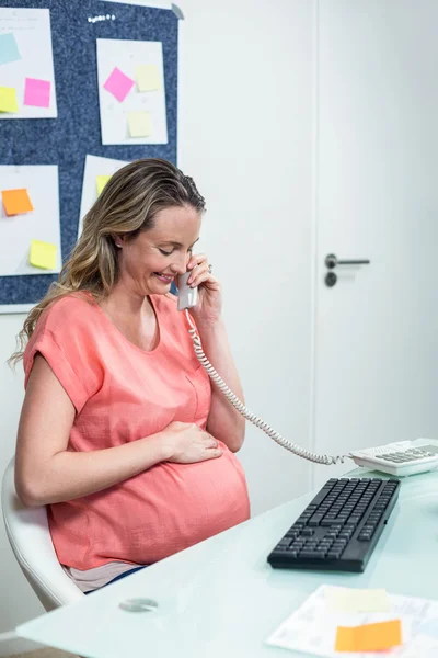 Pregnant woman using computer and phone