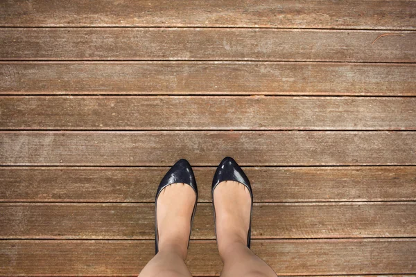 Businesswomans feet against wooden planks