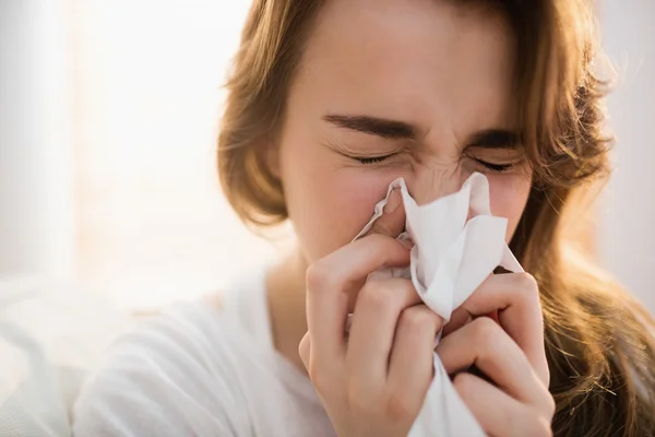 Woman blowing her nose on couch