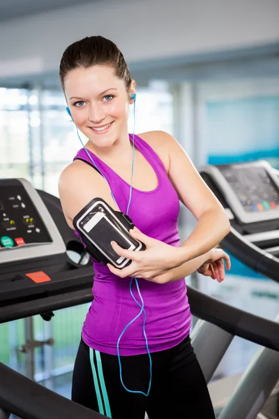 Smiling woman on treadmill using smartphone