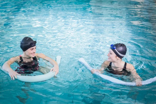 Smiling women in the pool with foam rollers