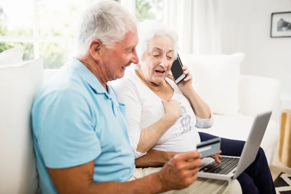 Smiling senior couple using laptop and smartphone