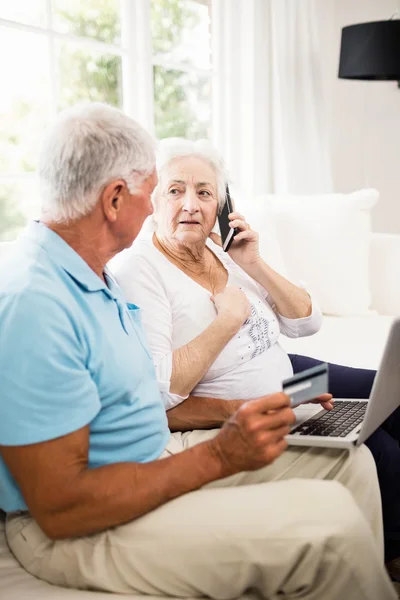 Smiling senior couple using laptop and smartphone