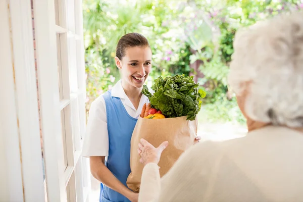 Nice nurse bringing vegetables to old patient