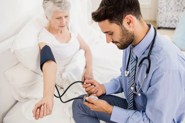 Handsome nurse checking blood pressure of elderly woman