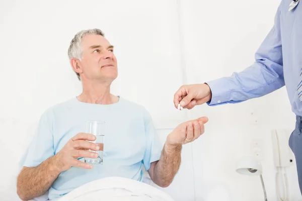 Male nurse giving pills to senior man