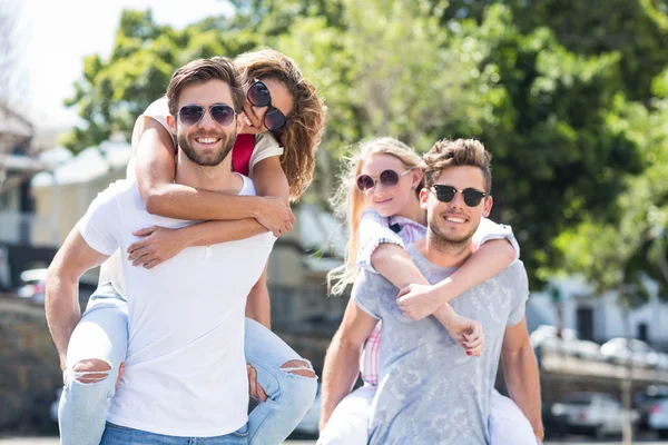 Hip men giving piggy back to their girlfriends